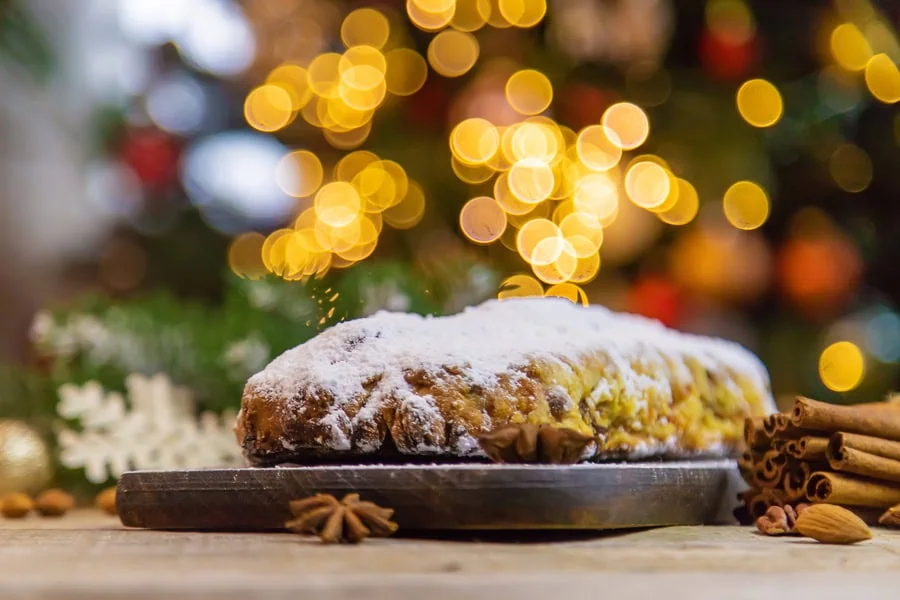 Weihnachtsstollen auf einem Tisch, im Hintergrund ein geschmückter Tannenbaum.